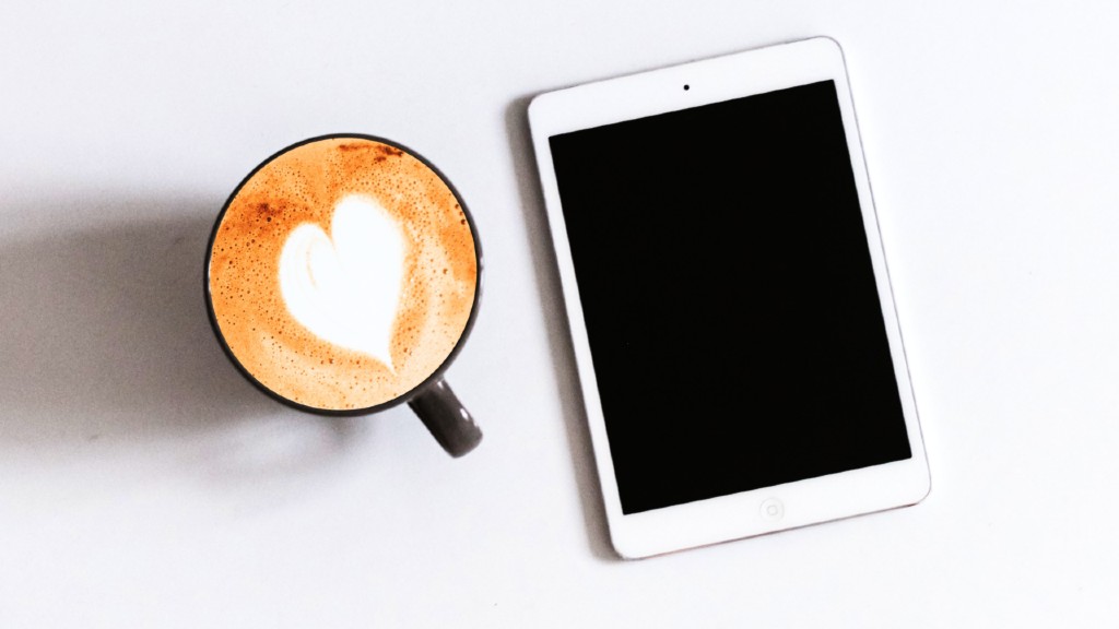 a cup of coffee next to a tablet  on a desk