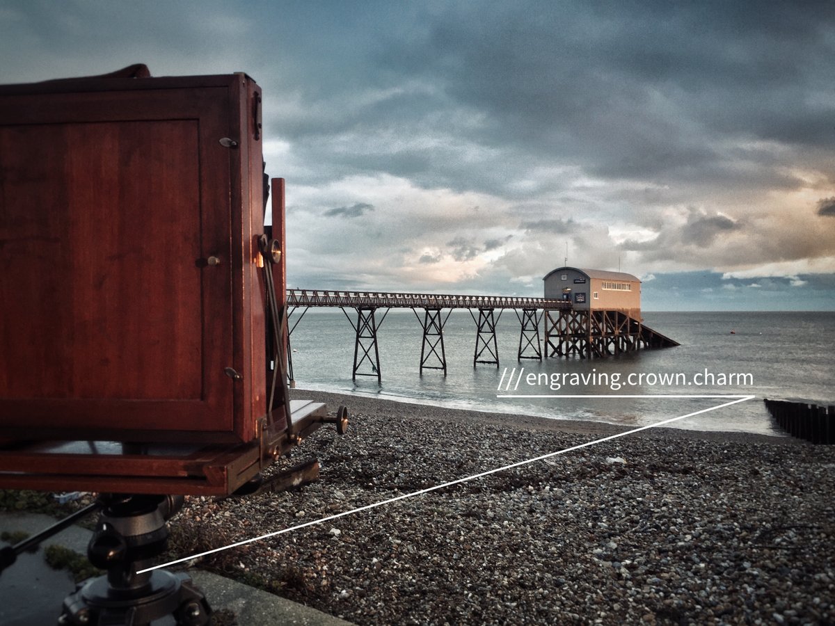 An old camera pointing at a lifeboat station on the see at ///engraving.crown.charm