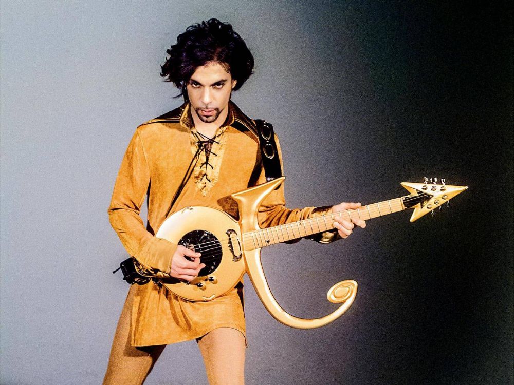 Over the years Prince has worn variations of tunics from dazzling coin encrusted fitted tunic to digitally printed polo-necks. He adapted the style adding lace up detailing, sheer panelling, opulent textiles & embellishments such as gold coins.