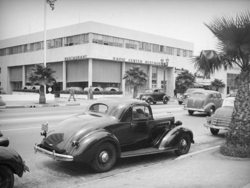 View of Radio City restaurant from across the street with cars driving down the street.