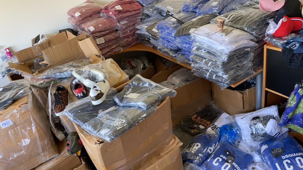 FIOD's tweet photo. Op 13 augustus vonden we ruim 7500 stuks merkvervalste #kleding en schoenen in loodsen in #Amsterdam, #Purmerend en Zwanenburg. De #vervalste merken waren o.a. #Versace, Dsquared, Stone Island en Louis Vuitton. 2 mannen (35 en 22 jaar) zijn verdachten. https://t.co/5dURVbE25c https://t.co/sSnmsV2a8R