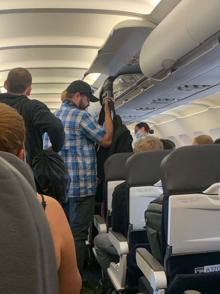 GinaDTucker's tweet photo. Some photos from my @AmericanAir flight- even the pilot was wearing his mask wrong! Many people were standing maskless in the aisles the whole flight. Unacceptable. https://t.co/oV7qvQ4K33