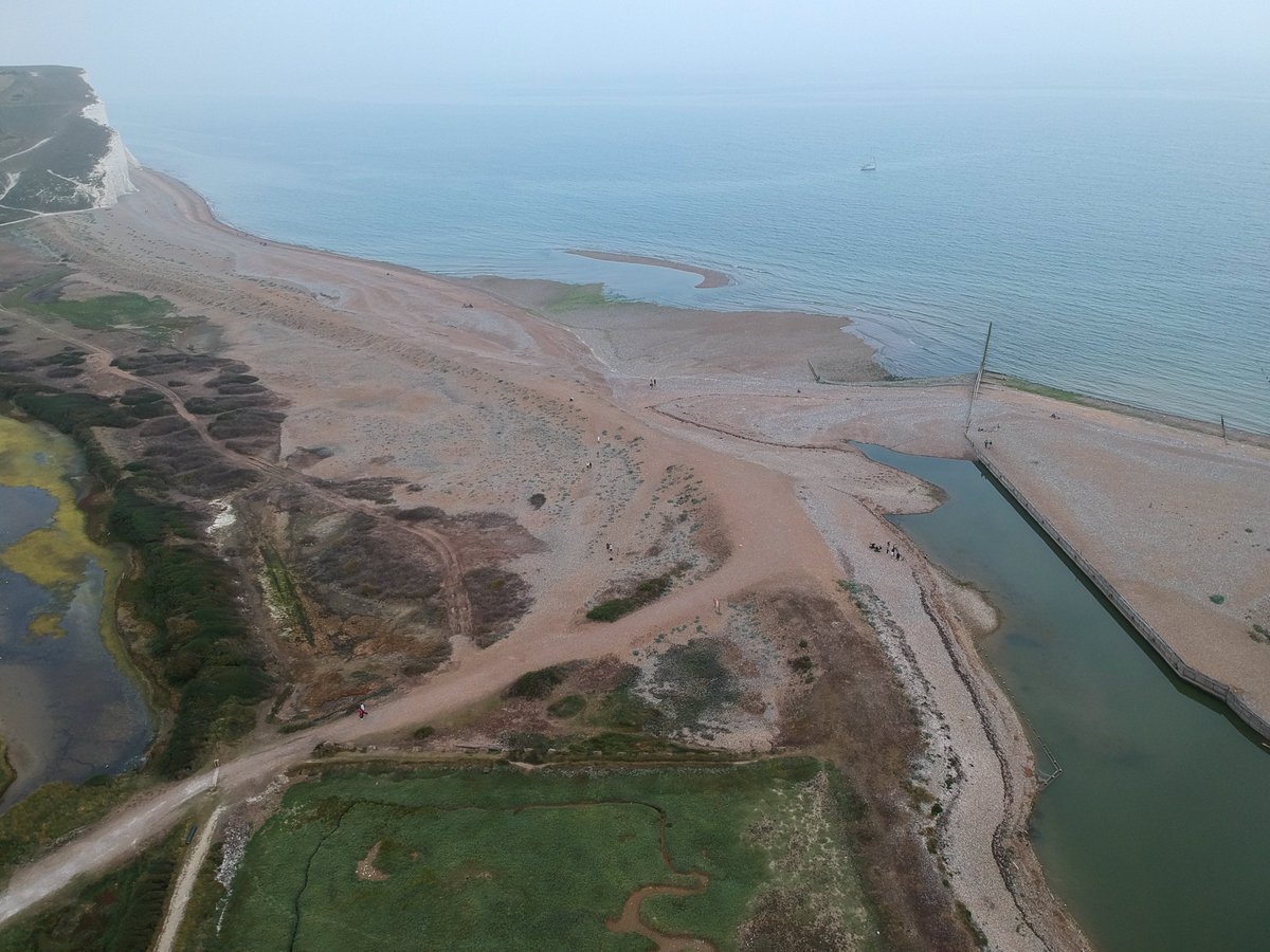 andrewgardnr's tweet photo. Aerial images showing the build-up of shingle where the River Cuckmere meets the sea. The river has not been able to run into the sea for weeks, and is turning stagnant, fish are dying, and it stinks. 
#seaford #cuckmere #southdowns #rivercuckmere #wildlife #sdnp #sevensisters https://t.co/T4LhVxo1TP
