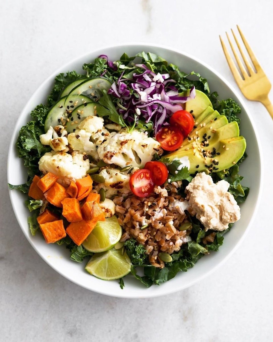 Fast and flavorful, this roasted cauliflower and sweet potato bowl is packed with veggies -- cauliflower, sweet potatoes, kale, cucumber, cabbage, cherry tomatoes (but feel free to change up the veggies with what you have on hand) -- hummus, avocado, farro, and a creamy cashew dr