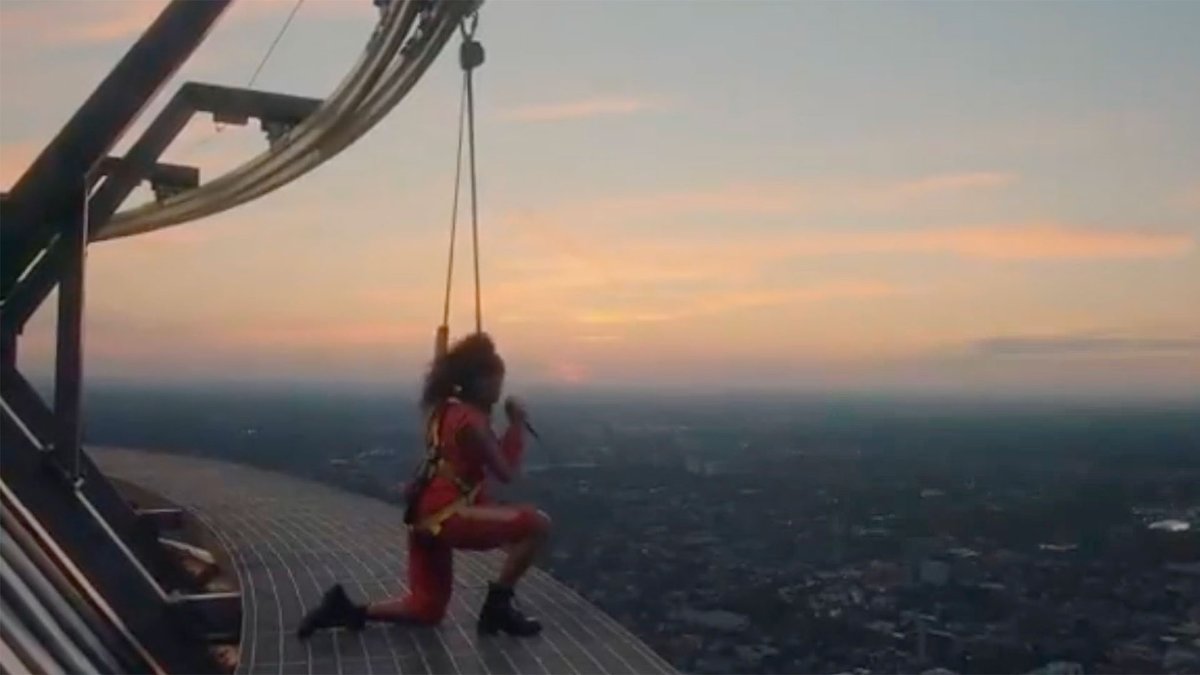 CP24's tweet photo. Toronto singer Jessie Reyez kneels atop CN Tower for 'O Canada' prior to Raptors playoff debut https://t.co/IIENwqkfzA https://t.co/hysqWhp9d4