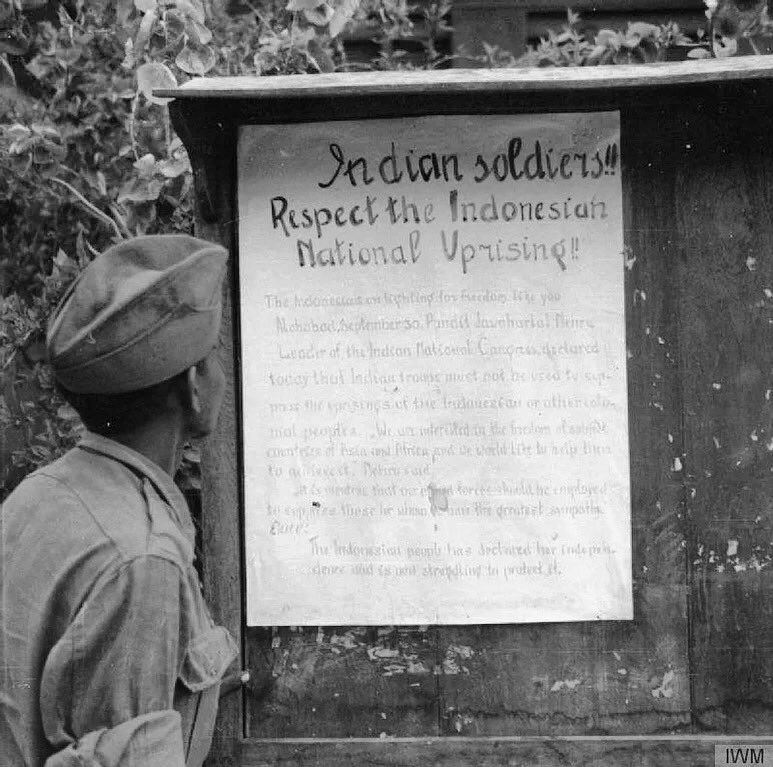 British Indian soldier reading an Indonesian nationalist poster during the Battle of Surabaya in November 1945. The poster reads: “Indian Soldiers!!! Respect the Indonesian National Uprising!!!”