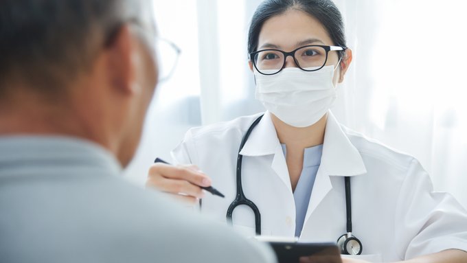 Imagen: Una doctora que lleva mascarilla habla con un paciente.