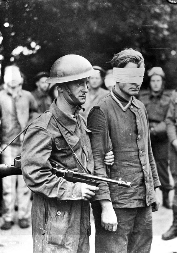 A Canadian soldier escorting a wounded German prisoner, captured during the Dieppe raid, England. 19 August 1942. LAC MIKAN: 3592340.