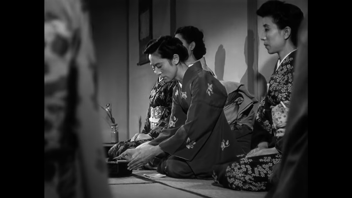 Another careful composition. Note the vase in the far corner that fills out the empty space in the background, and again we have shoulders in the extreme foreground to provide another plane. Despite the sharp angle Ozu’s 50mm lens still gives the impression this is a flat image.