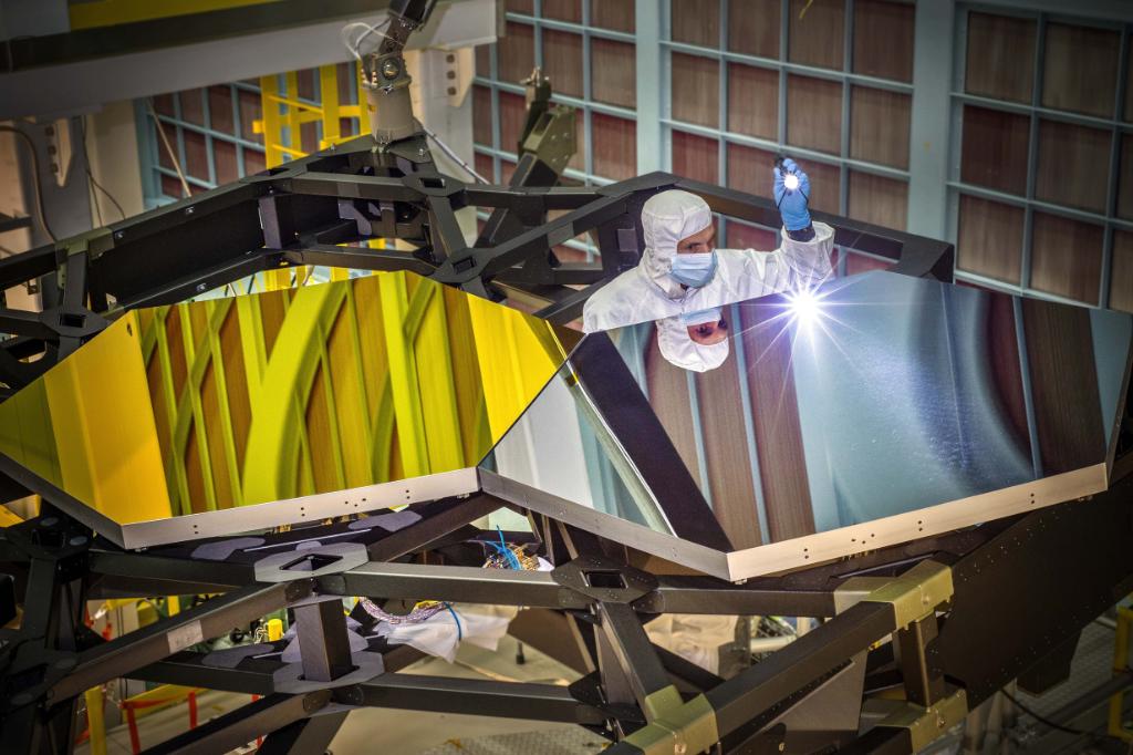 In this photo from 2014, JWST Optical Engineer Larkin Carey examines two test mirror segments placed onto a black composite structure.