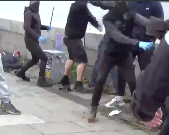 Here you can see a fascist armed with a baton on the left, behind him an anti fascist lies unconscious on the ground wearing red trainers. Blue gloves are so fingerprints aren't left on the weapons, most of this fascist group at the anti-mask rally were wearing masks /3