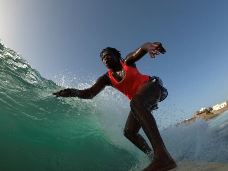 あーつ セネガル初で唯一の女性プロサーファー 首都ダカールの沿岸で育ったカジュー サンベさんは14歳で叔父やいとこと共にサーフィンを始めた サーフィンをする女性は他に誰ひとりいなくて周囲に奇異の目で見られたりからかわれたが おばあちゃんは常に