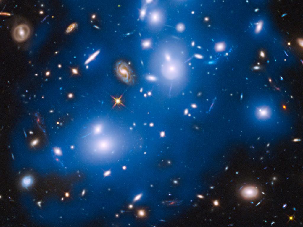 Dozens of galaxies in Abell 2744. The image has a blue glow. 