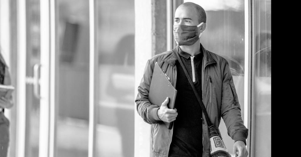 man in mask walking into building