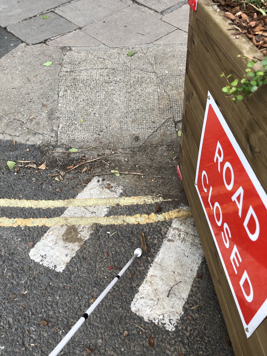 I have found the placement of the road blocks inconsistent, with varying distances from drop curbs & including some that absolutely block access.Given the new obstacle created by the boxes, it is vital that appropriate tactile paving is installed to direct pedestrian flow.