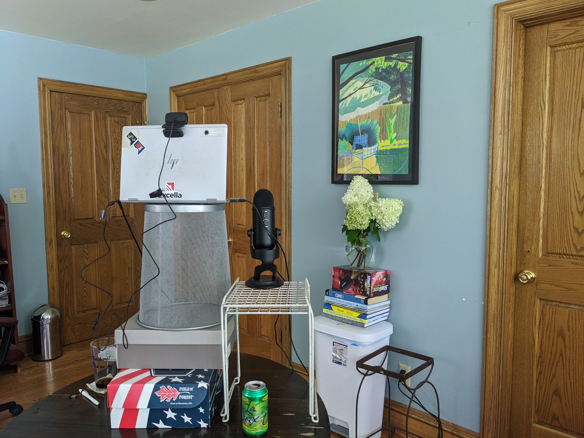 Photo of a table with a stack of shoeboxes, an overturned garbage can, and other items propping up a laptop, mic, and webcam