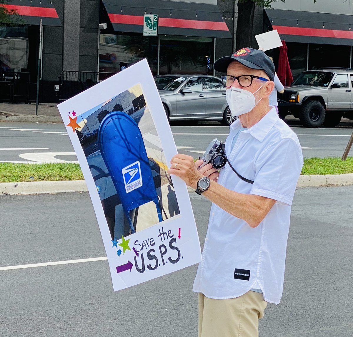 Protest sign shows an image of a post office box and says “Save the USPS.”
