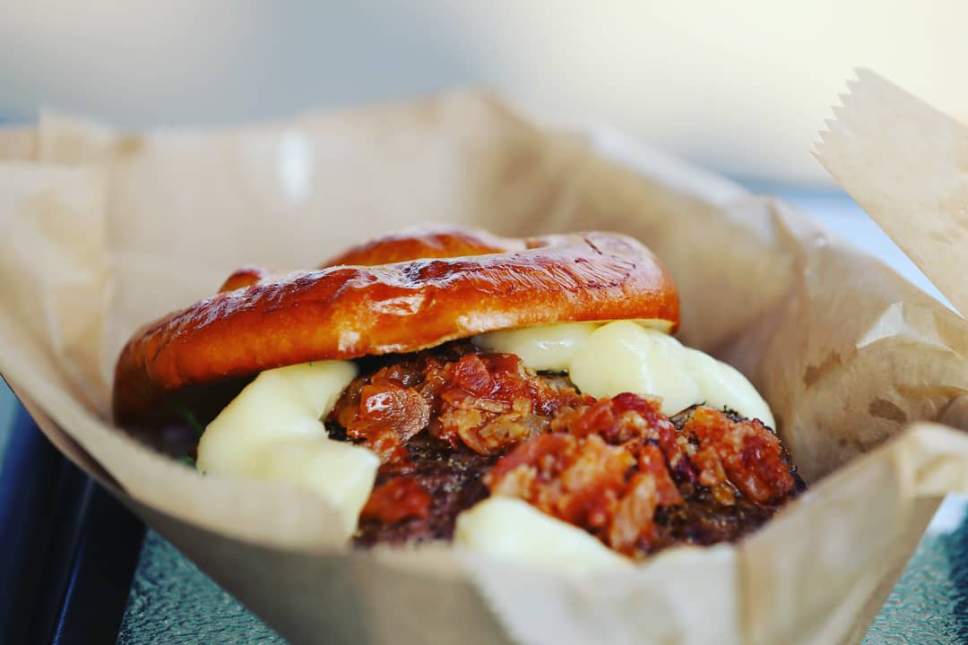 This is The Winchester Burger from  @TheWinchesterGround Ohio beef with cheddar cheese curds, bacon jam, sun-dried tomato aioli, pickled red onion, sliced house pickles and greens, served on a pretzel bun.   #BurgerWeekCLE @CLEburgerweek