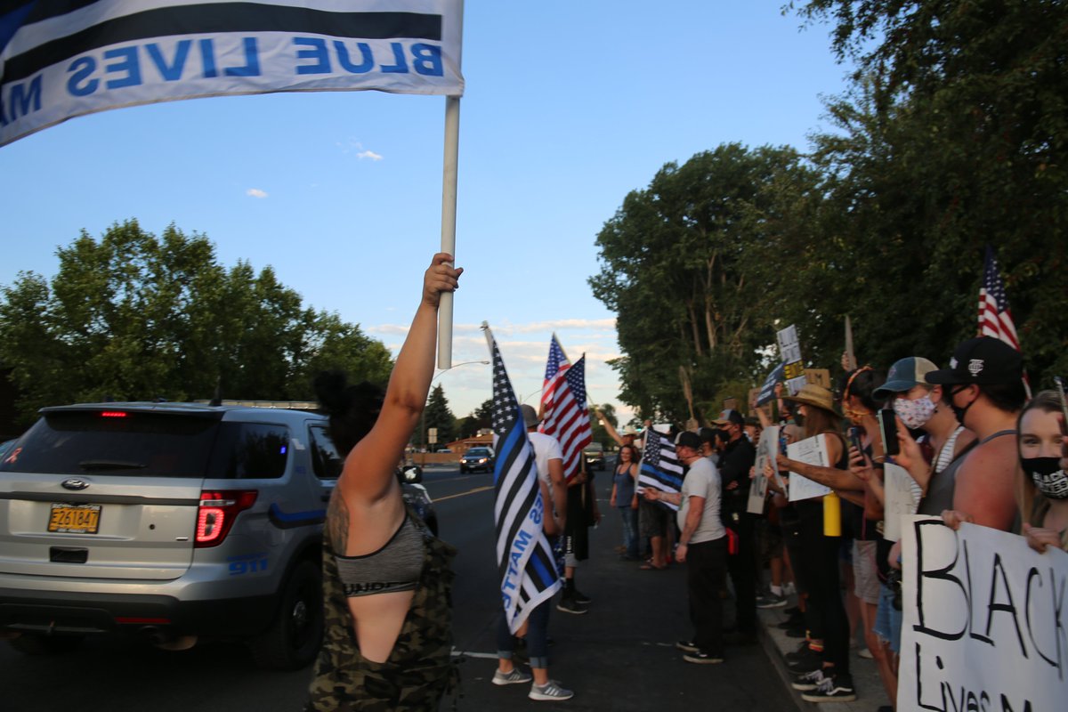 The conflict spread offline into weekly protests and counterprotests.In front of the county courthouse distinct groups face off from either side of a state highway. Passing traffic revs and honks.