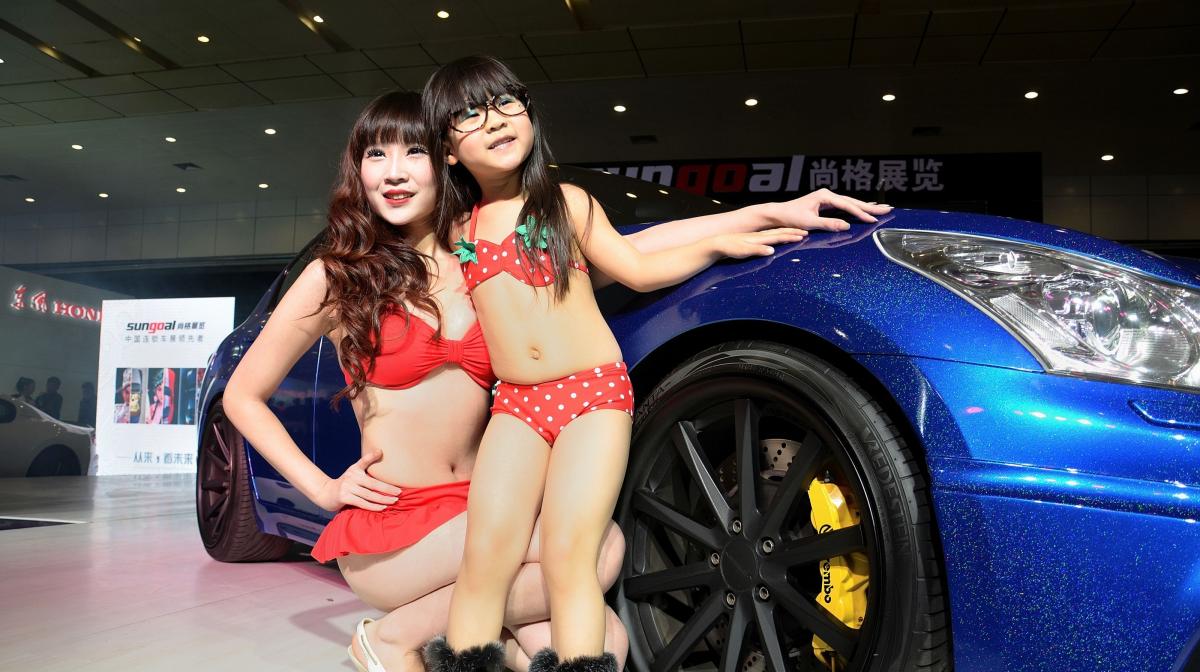 5yo girls in high boots, posing with a professional sway in front of sedan models exhibited last week in the city of Wuhan...