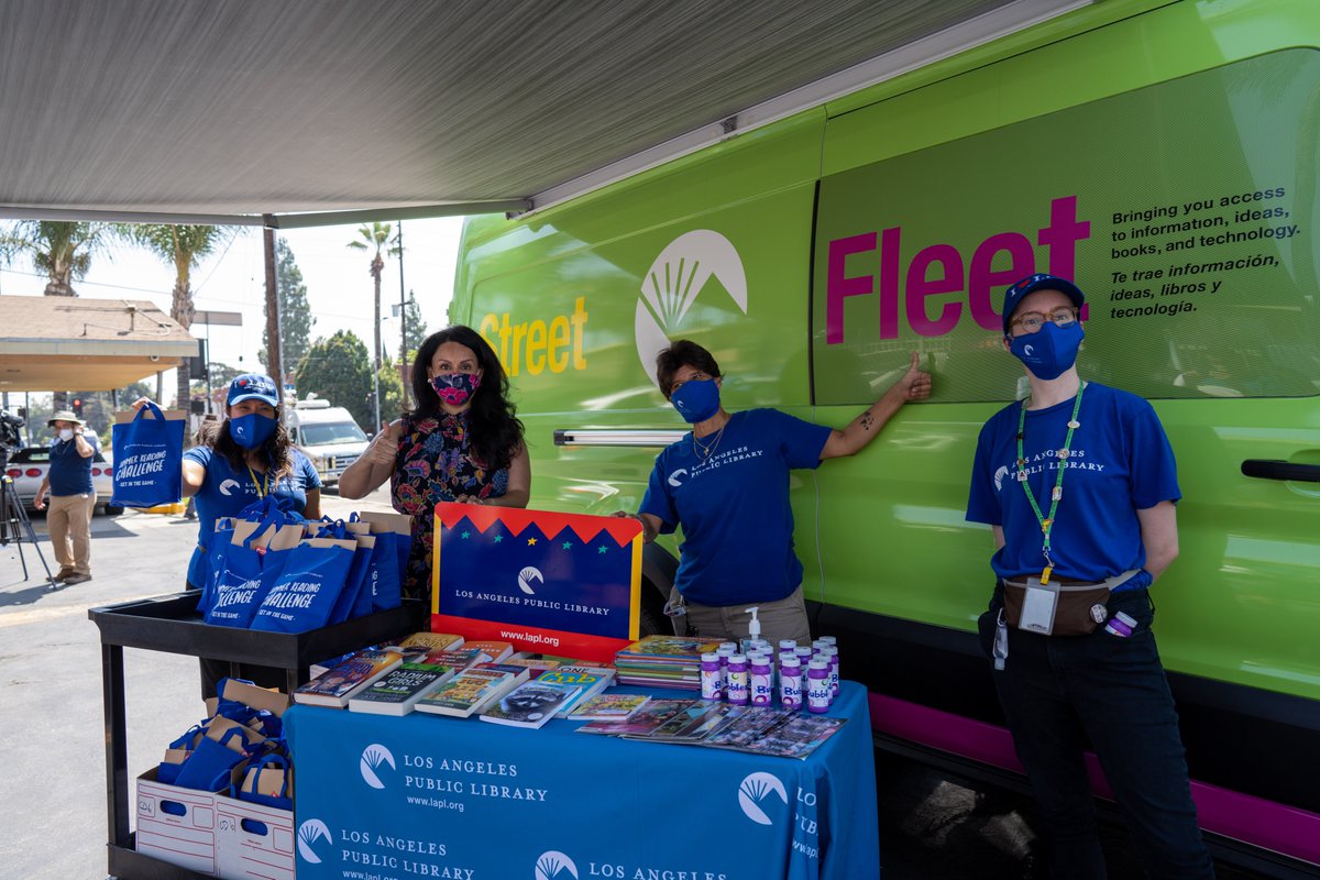 Three LAPL staff and Nury Martinez in front of street Fleet van holding library card and Summer Reading Challenge bags.