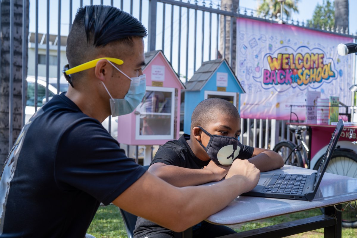 Child with a tutor working on a laptop.