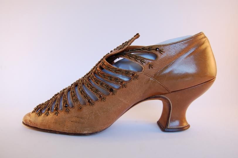 NorwichCastle's tweet photo. This woman’s shoe is made from light brown kid and dates from around 1900. The bars along the top of the shoe are decorated with gold beadwork, while the heel curves inwards in the Louis XIV style. What type of event would you wear this to? https://t.co/ZWMUKVE8ol