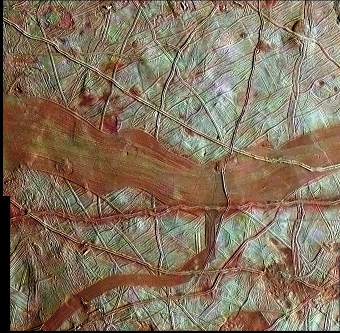 Close-up view of the moon Europa, which has an icy white surface crisscrossed by reddish-brown fractures and ridges.