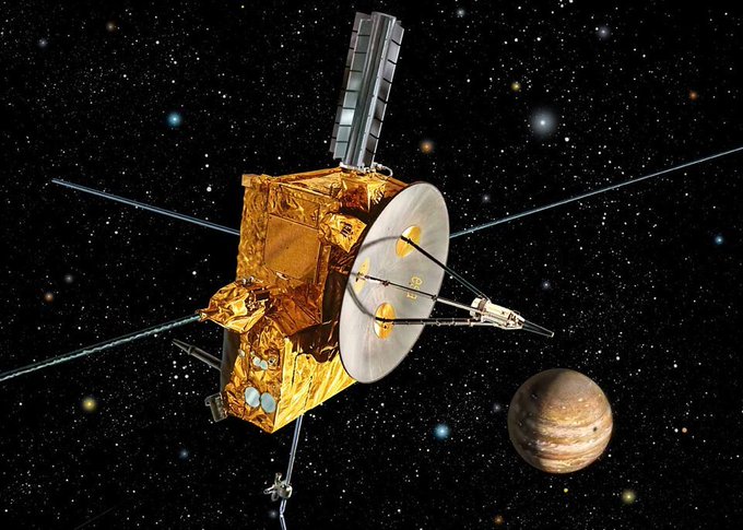 Artist's rendition of Ulysses spacecraft, rougly rectangular with a satellite dish and several antennae, with the main body of the craft covered in gold foil. In the background is an image of Jupiter. 