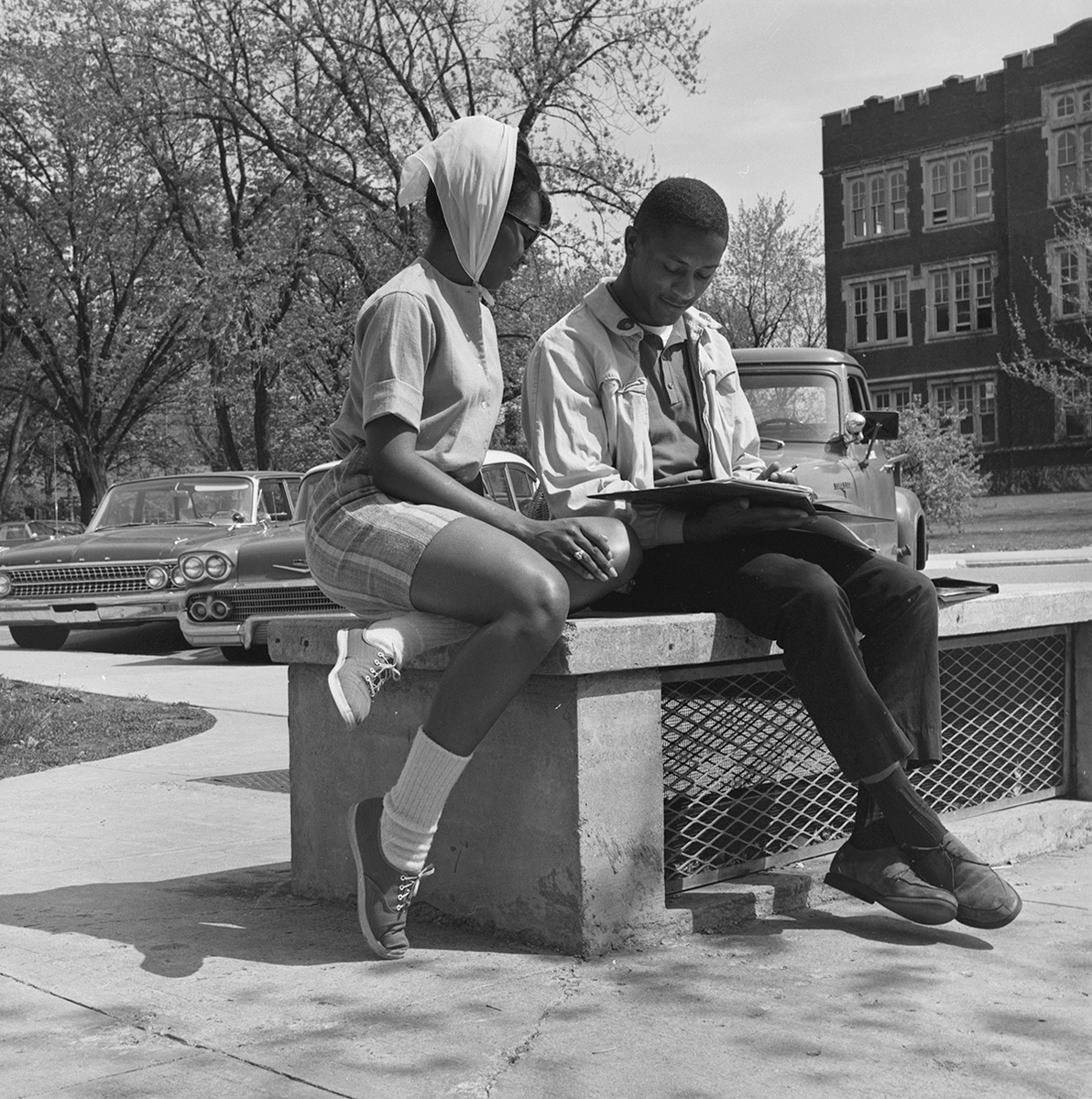 BallState's tweet photo. Two students take a break to read on a bench along Ball State’s circular drive just north of the Administration Building in the 1960s. #ThrowbackThursday #TBT https://t.co/NIRDnz6Sg9