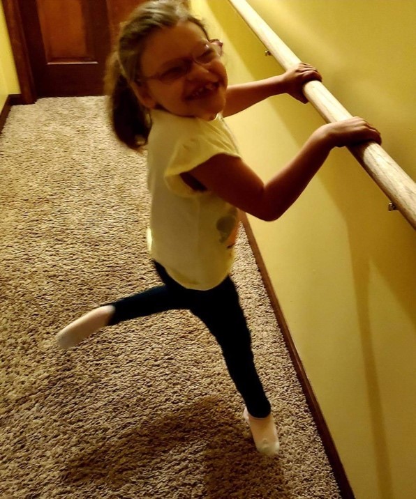 She’s asking to walk more and more and we’re able to hold lower on her body to support her – at her pelvis vs. trunk or arms. We’ve installed a railing down the hallway that she now uses multiple times per day and will lift one leg up in what she calls a “ballerina” move.