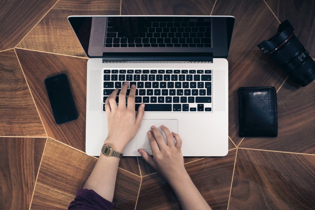 a woman working on her laptop on top of a large wooden table