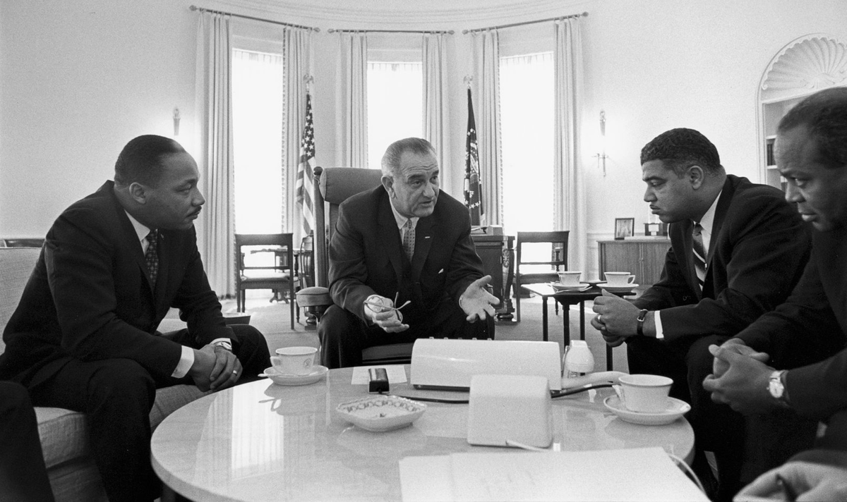 President Lyndon Johnson in the Oval Office with Dr. Martin Luther King, Jr. and other African American leaders.