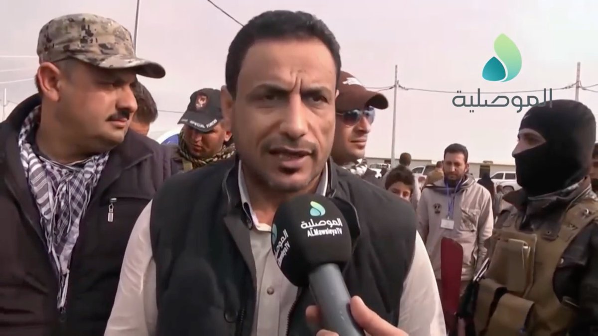 A smiley, wrinkly guy.The security chief tells the Iraqi Counter Terrorism Service (CTS) guy "He's with me."The man in the aviator sunglasses confirms it to the CTS guy.