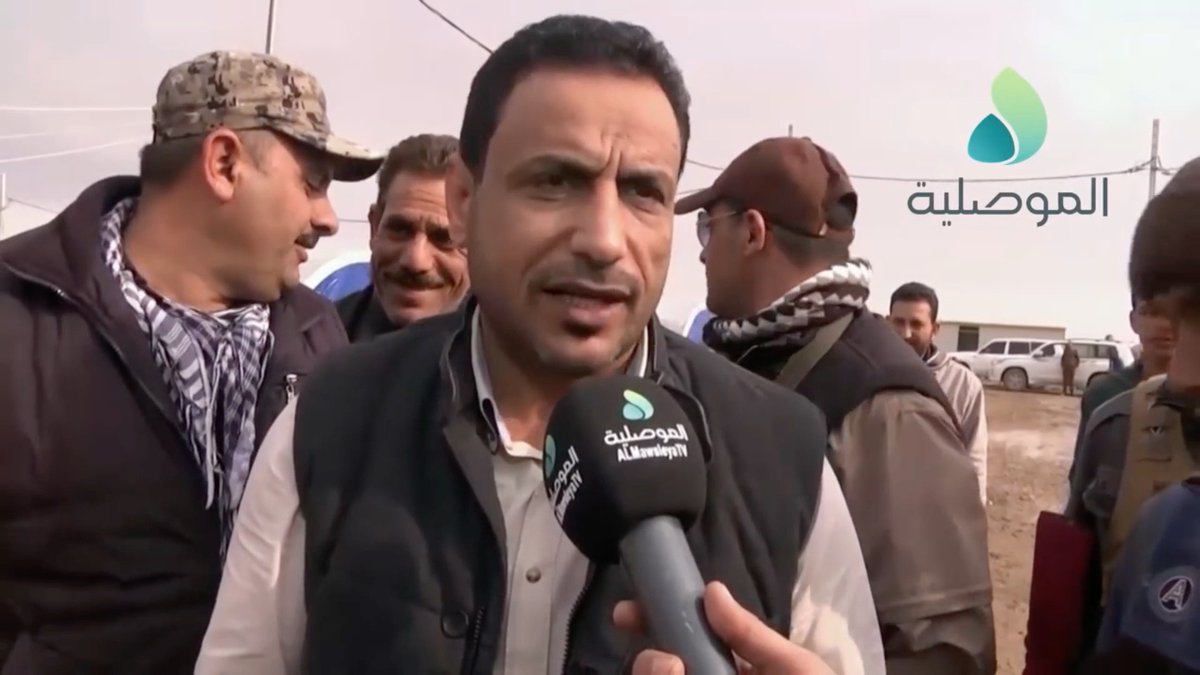 A smiley, wrinkly guy.The security chief tells the Iraqi Counter Terrorism Service (CTS) guy "He's with me."The man in the aviator sunglasses confirms it to the CTS guy.