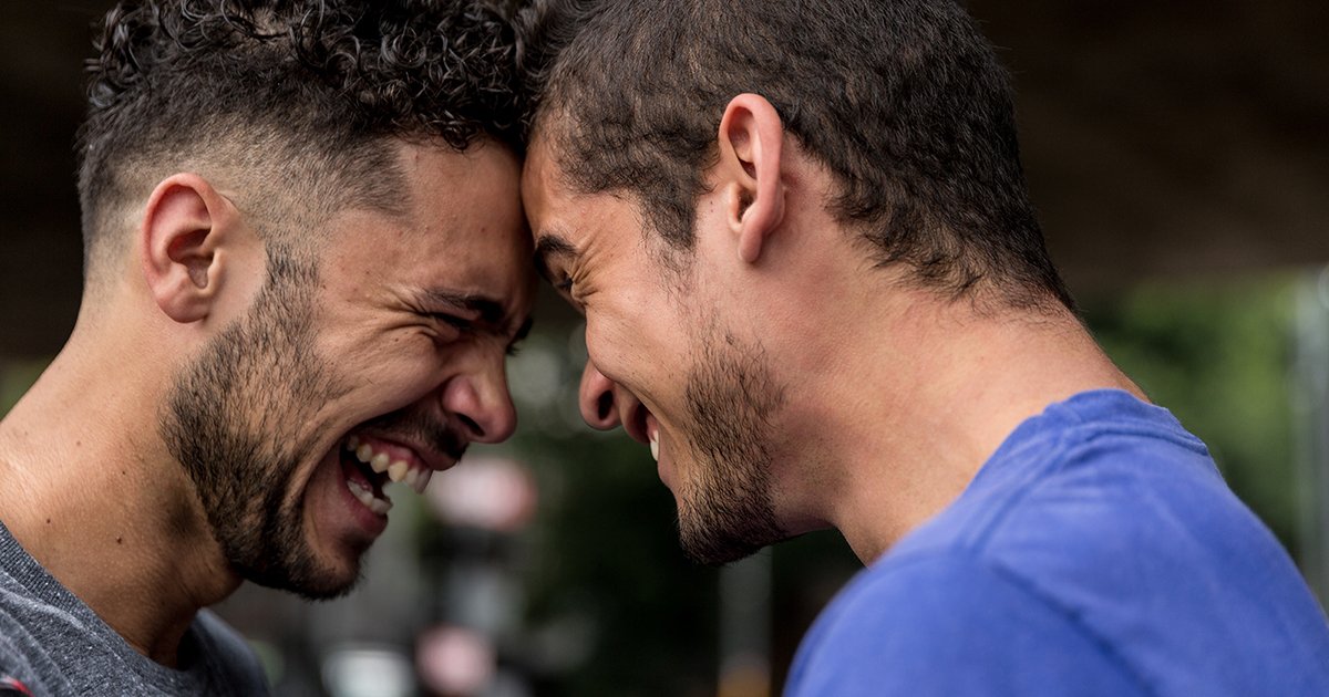Two men looking into each other's eyes, smiling and touching foreheads