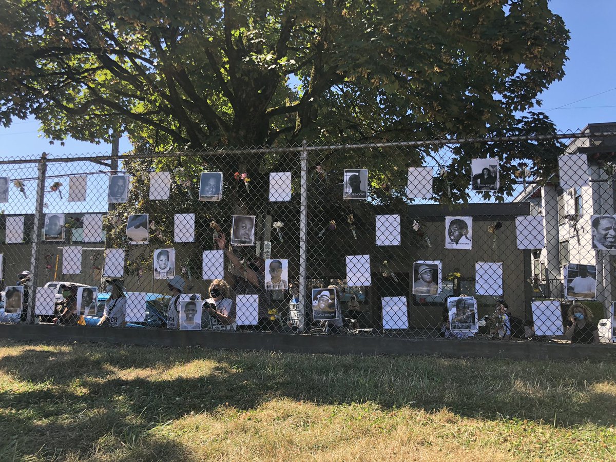 As the crowd fills the park outside Revolution Hall, they’re met with free pizza, hand sanitizer and a concert stage. Flowers, banners and photos of Black victims of police killings are threaded through the park’s fences.