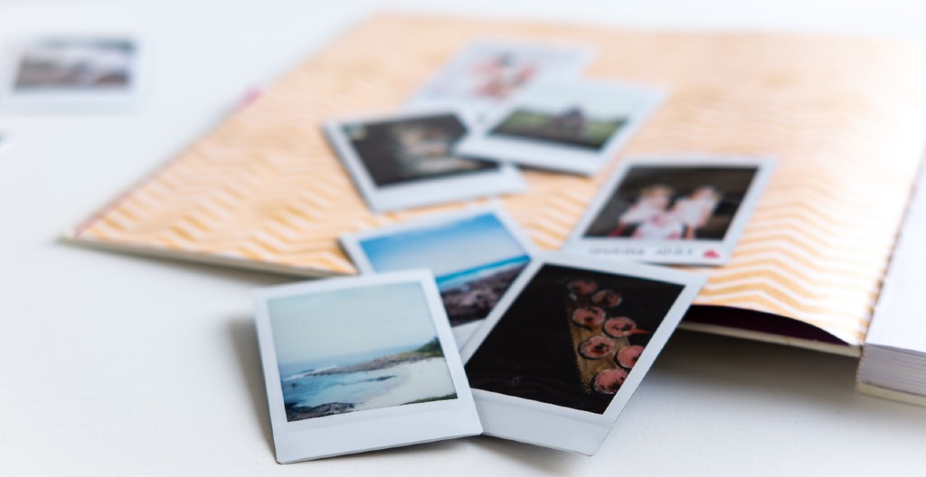 a photo album open with various polaroids strewn about open pages