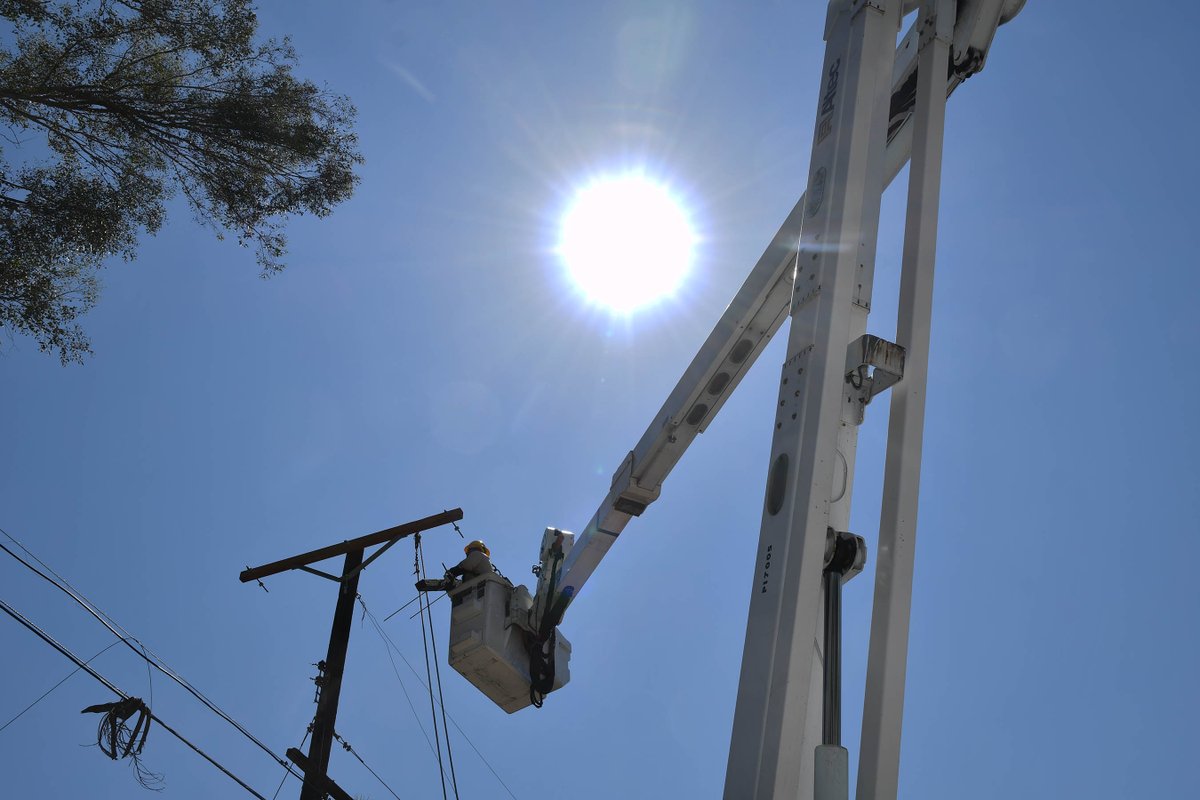 Image of utility worker in bucket vehicle with sun beating down above.