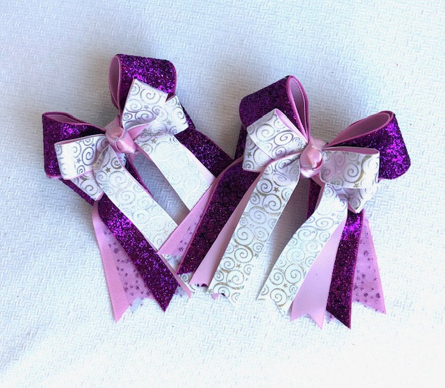 ChiefBowdangler's tweet photo. One pair of this new design is Ready2Mail with clips.  They are smaller bow in a beautiful and vibrant violet glitter that doesn't shed with more glitter underneath topped with a bright white with a silver sparkle swirl.  Eye-catching! https://t.co/vVJGgOGaDQ