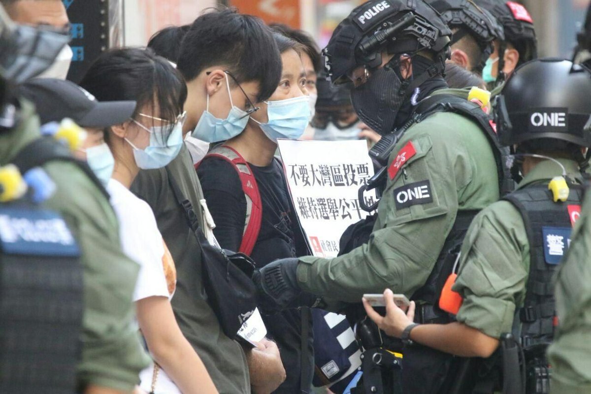 VerbatimHKG's tweet photo. 1530: riot police stopped and searched everyone including pedestrians at the exit of Man Ming Lane at Yau Mei Tei MTR. 

Police hoisted a blue flag as a warning. Photos captures the young and old, encircled by the police on a Sunday originally set to vote for Legislative Council. https://t.co/VBUHhgPGu6