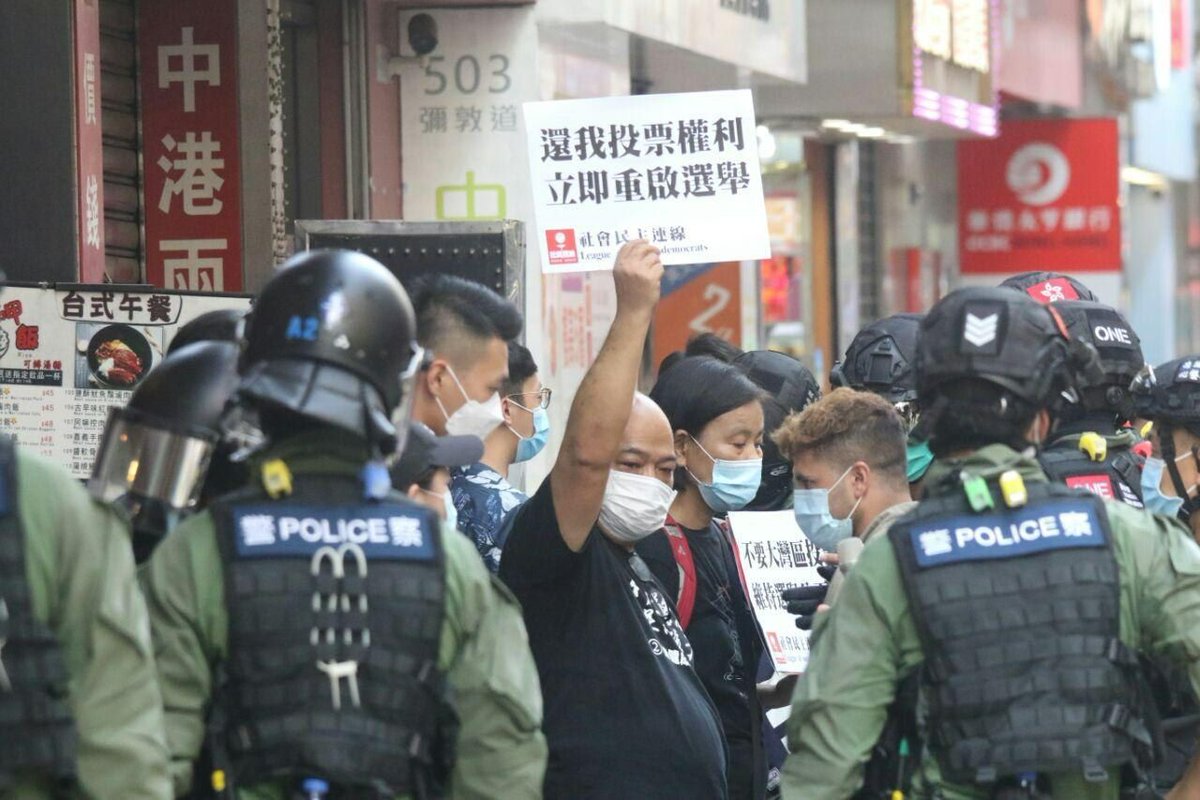 VerbatimHKG's tweet photo. 1530: riot police stopped and searched everyone including pedestrians at the exit of Man Ming Lane at Yau Mei Tei MTR. 

Police hoisted a blue flag as a warning. Photos captures the young and old, encircled by the police on a Sunday originally set to vote for Legislative Council. https://t.co/VBUHhgPGu6