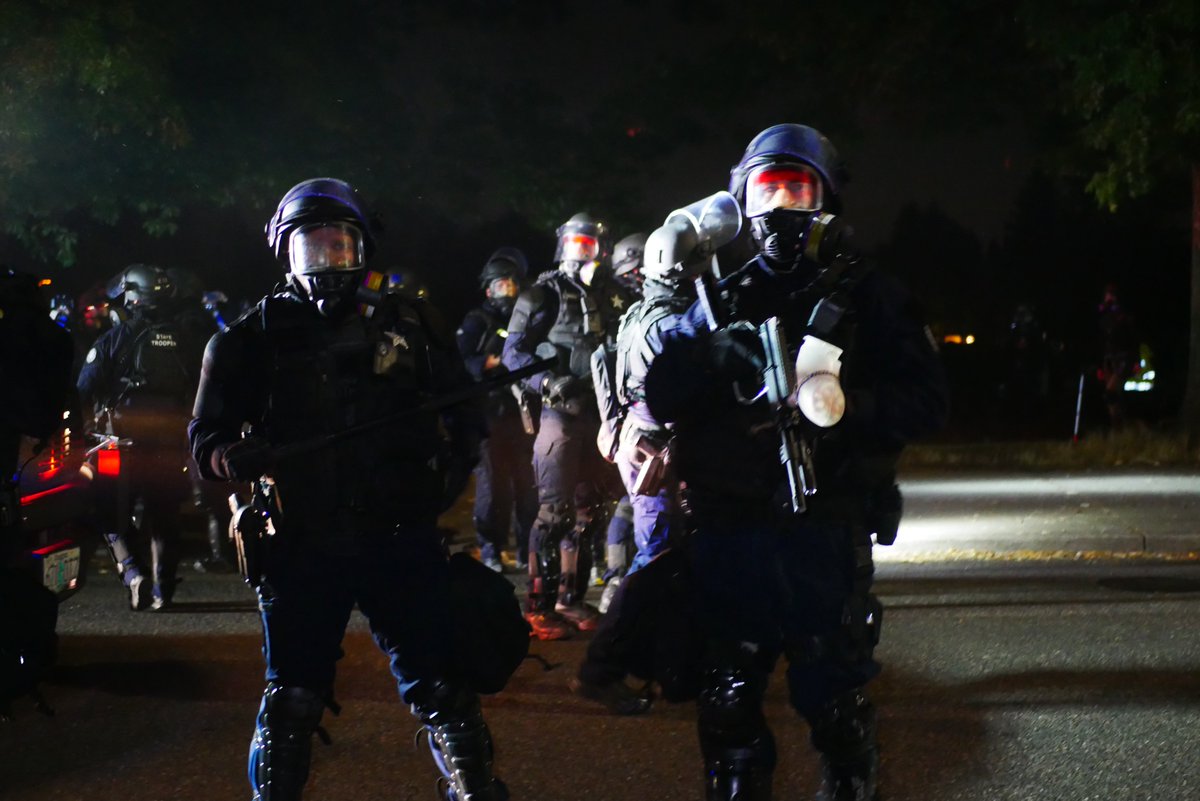 9/5 2302-2303 Officer with a pepper ball gun looks for protesters down a side street, tells an individual "cross the street and see what happens." #pdxprotest  #BLM  #portland  #blacklivesmatter    #portlandprotest  #defendpdx  #BLMprotestsvideo:  https://twitter.com/BaghdadBrian/status/1302532601941356545