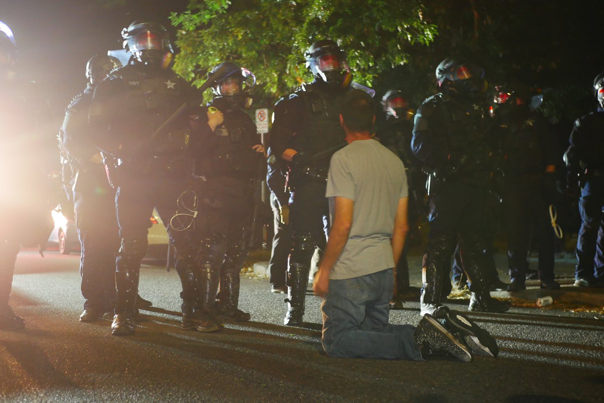 9/5 2305-2307 Officer points rifle with mounted light at protester in gray. He's joined in front of the line by another protester, before briefly kneeling in front of the police. #pdxprotest  #BLM  #portland  #blacklivesmatter    #portlandprotest  #defendpdx  #BLMprotests