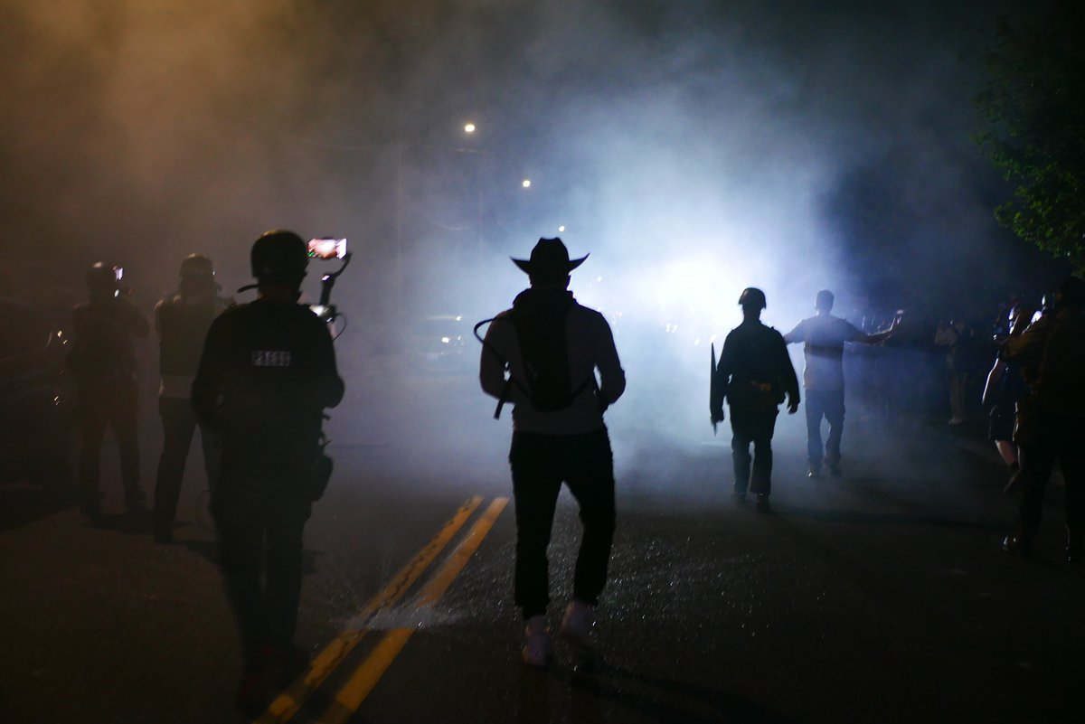 9/5 2318 A series of shots of a protester in a cowboy hat, silhouetted by police lights as the protest follows the retreating officers.  #pdxprotest  #BLM  #portland  #blacklivesmatter    #portlandprotest  #defendpdx  #BLMprotests