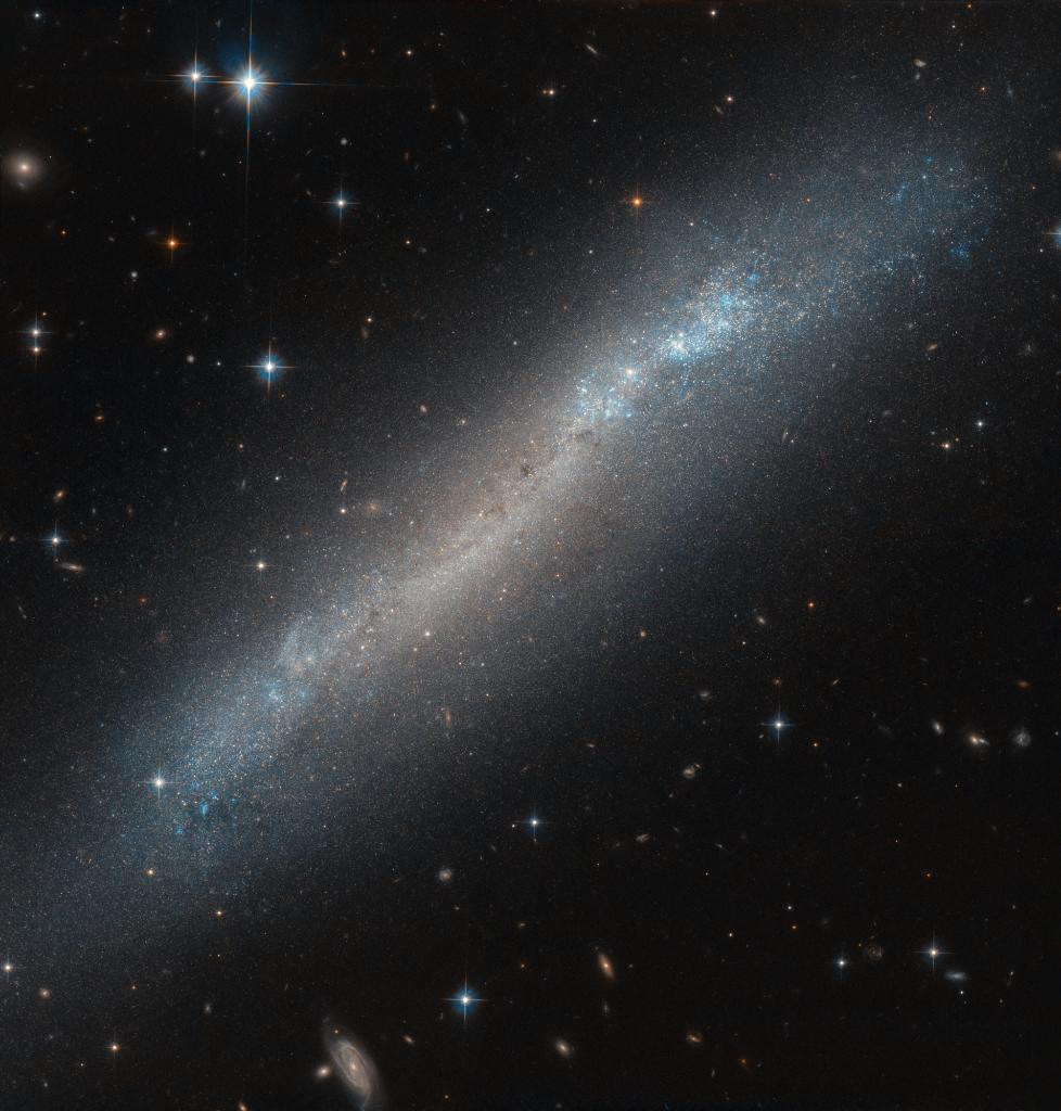 Blue and orange stars in galaxy appearing tilted sideways in a narrow band across deep space