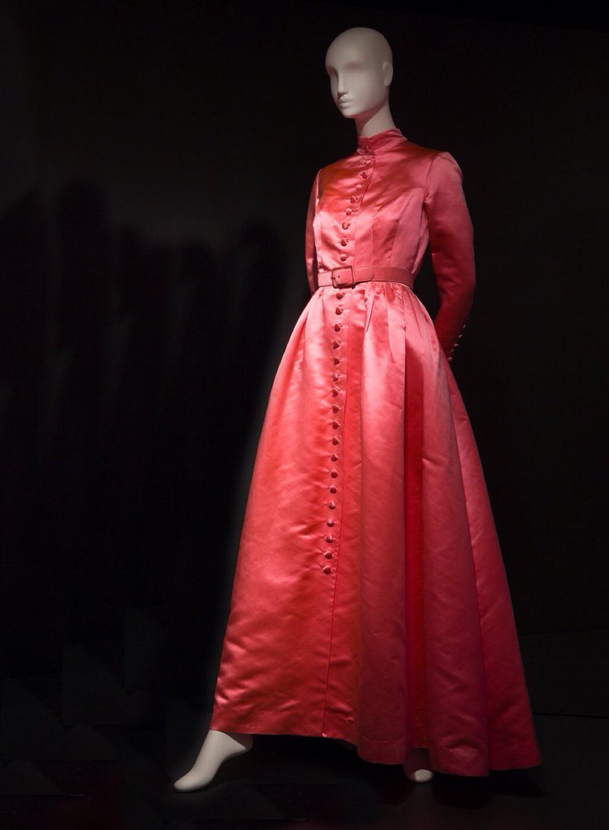 This gal looks like she is up to something dastardly. Emerging from the shadows in her shocking pink satin #coatdress, hands concealed behind her back, there is mischief afoot. What is she carrying & who is the object of her misdeeds? #TrainaNorell 1950 @museumatFIT #femmefatale