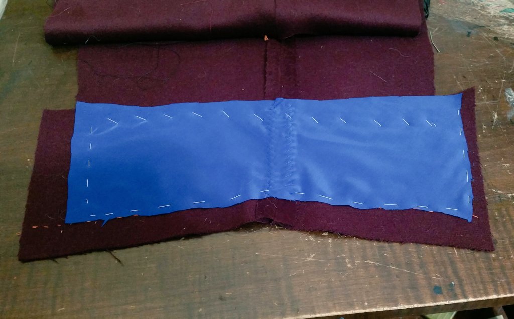 Getting the sleeves ready. A piece of pocketing is used to reinforce the area. The book said not to trim away the excess fabric in these mitered edges, but my fabric is so thick I did so. You also don't clip the seam allowance at the vent, just press it diagonally