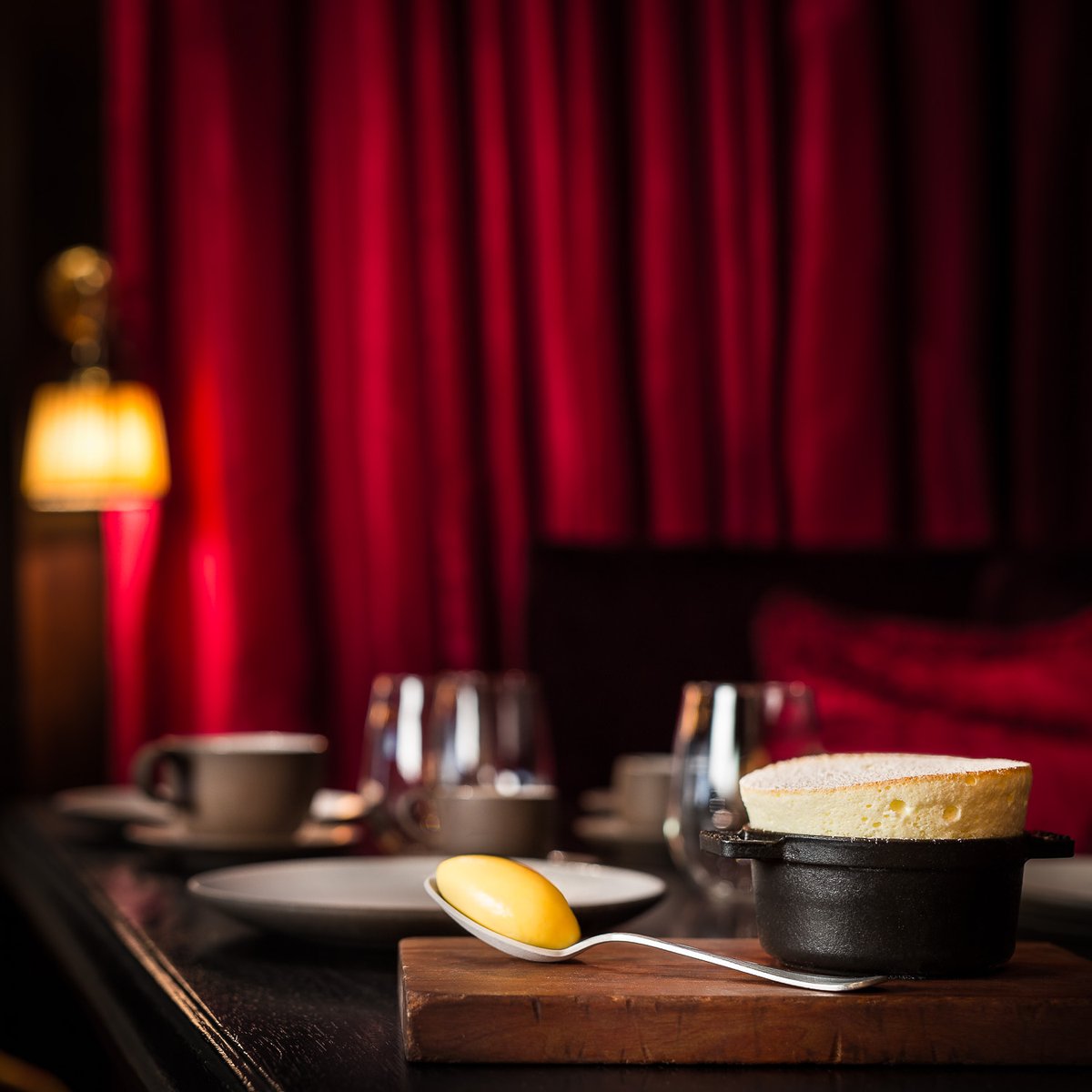 Speak soufflé, and carry a big spoon 🍨🥄

A dessert soufflé in a mini staub cast iron cocotte accompanied by a silver spoon holding a quenelle of sorbet presented on a wooden board on a set table at The NoMad Restaurant, NYC