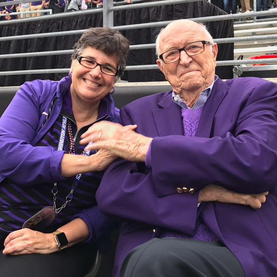 President Ana Mari Cauce with Bill Gates Sr. sitting on the sideline at a Husky Football game